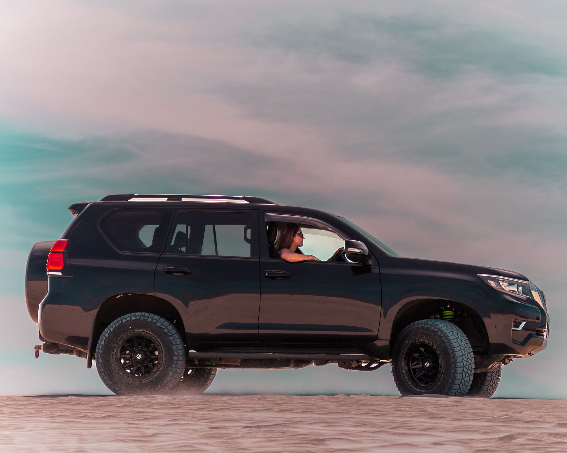 A 4x4 vehicle driving over desert sand dunes