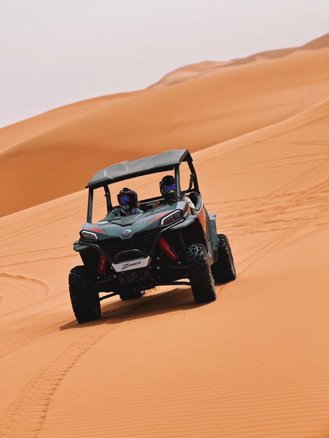 A quad bike riding over the orange dunes of the desert